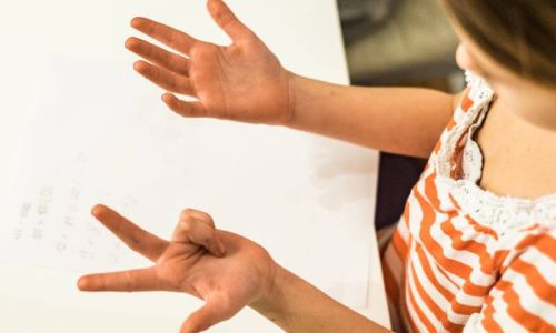 Una bambina si guarda le mani e conta le sue dita