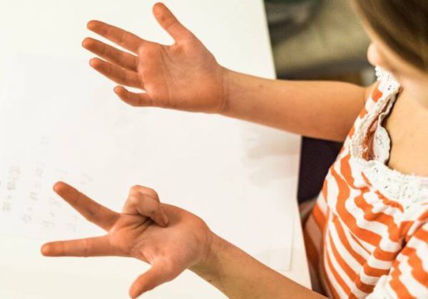 Una bambina si guarda le mani e conta le sue dita